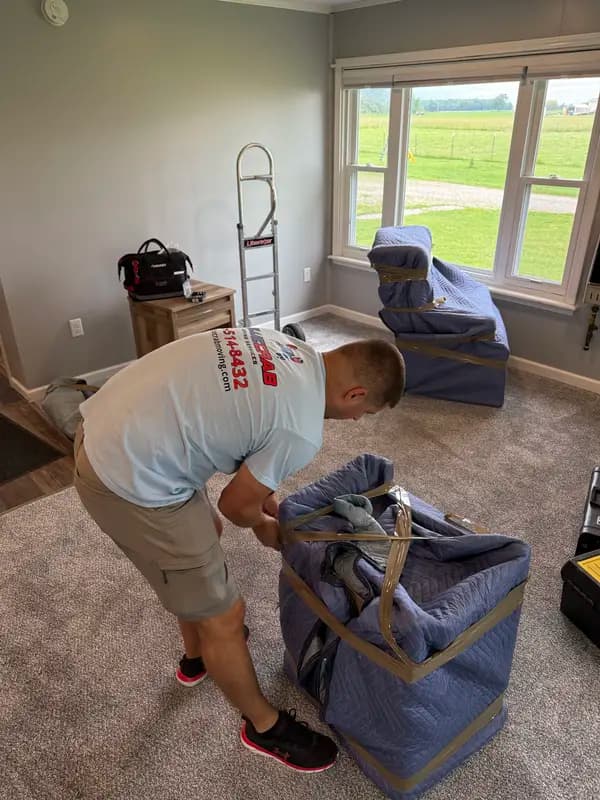 Blue Crab mover strapping moving blankets around furniture before the load out.